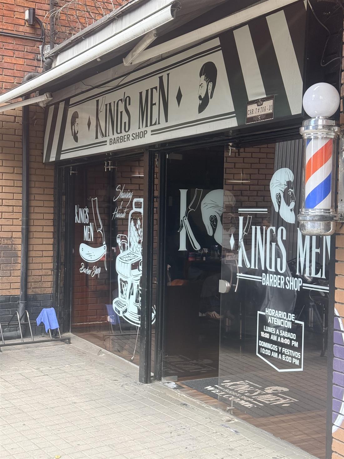 Fachada de KingsMen con el logo en el vidrio y el poste de barbero